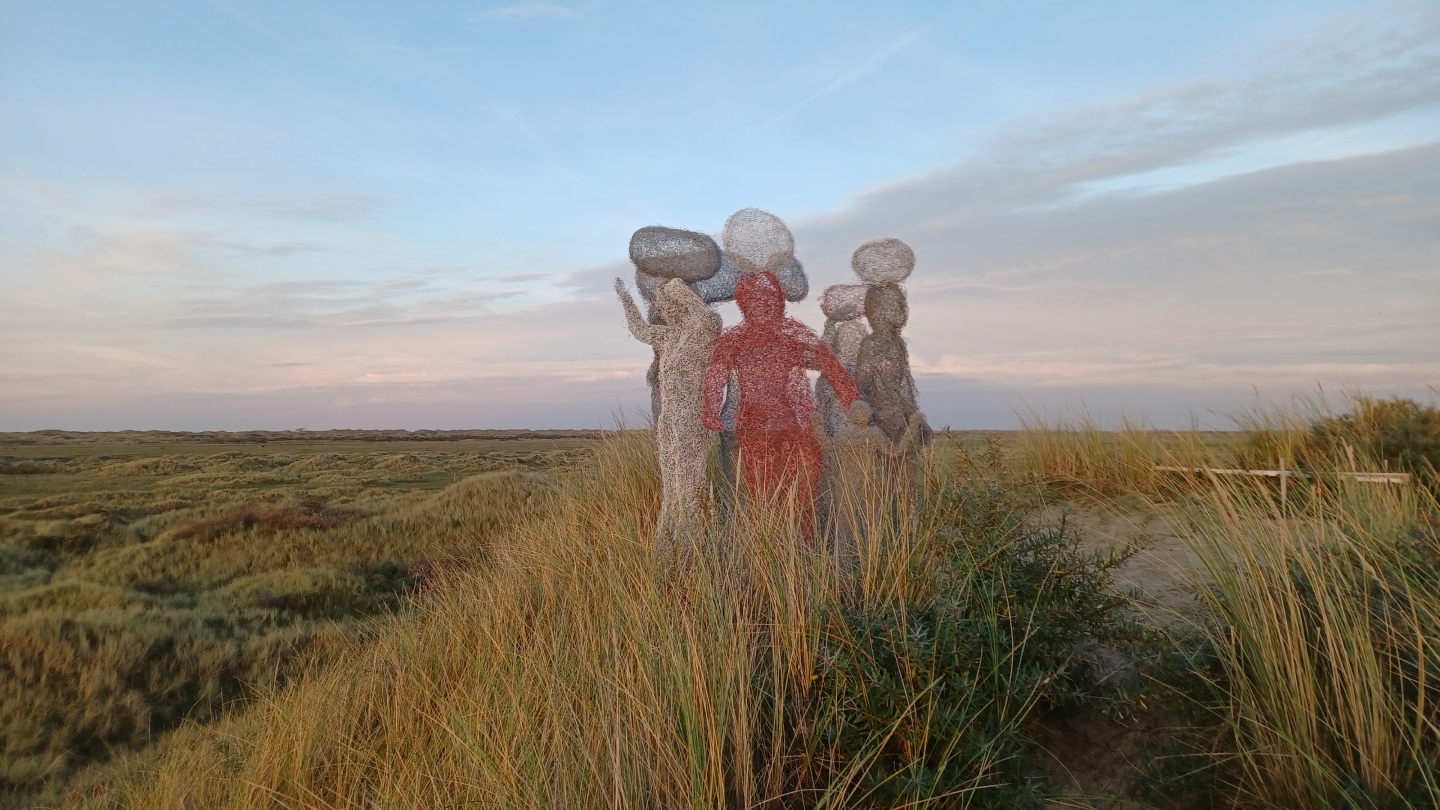 Een groep kleurrijke sculpturen tussen helmgras in het duinlandschap van Ameland, uit het Kunstmaand-beeldarchief